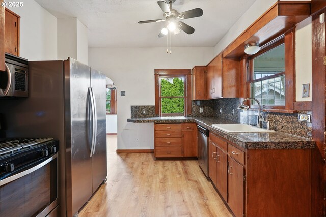 kitchen with sink, light hardwood / wood-style flooring, decorative backsplash, ceiling fan, and appliances with stainless steel finishes