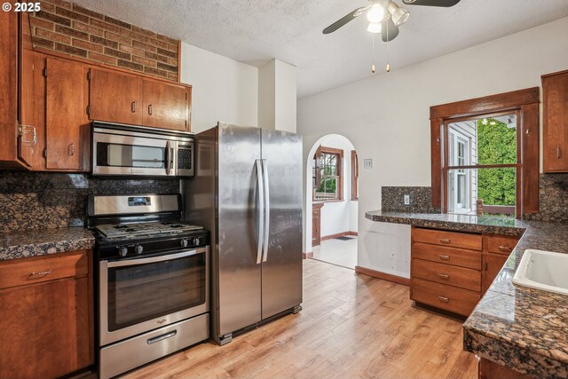 kitchen with decorative backsplash, appliances with stainless steel finishes, a textured ceiling, ceiling fan, and light hardwood / wood-style floors