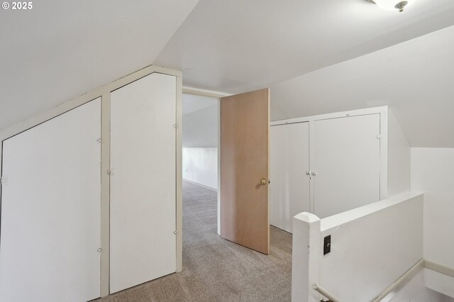 hallway with light carpet and lofted ceiling