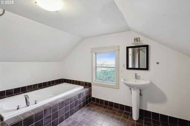 bathroom featuring tile patterned floors, a relaxing tiled tub, and vaulted ceiling