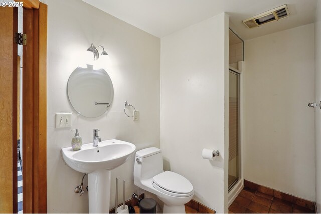 bathroom featuring tile patterned flooring, toilet, and a shower with door