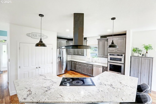 16295 SE Slate St, Damascus, OR 97089 - kitchen with appliances with stainless steel finishes, island exhaust hood, light wood-type flooring, tasteful backsplash, and light stone counters