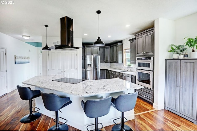 16295 SE Slate St, Damascus, OR 97089 - kitchen with island range hood, appliances with stainless steel finishes, a center island, a breakfast bar, and light wood finished floors