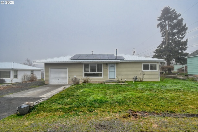 ranch-style house featuring solar panels, a front yard, and a garage