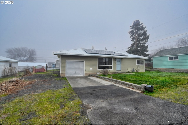 view of front of home with solar panels, a front lawn, and a garage