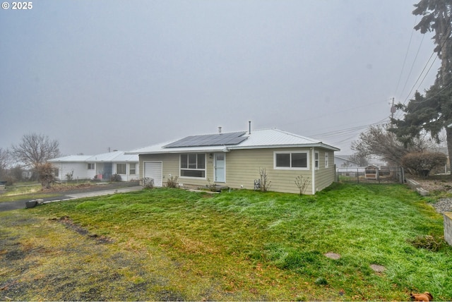 back of property with solar panels and a yard