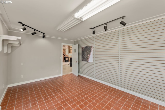 spare room with baseboards, ornamental molding, and track lighting