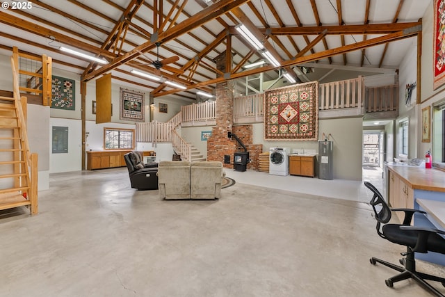 living area with stairs, high vaulted ceiling, washer / clothes dryer, and concrete floors