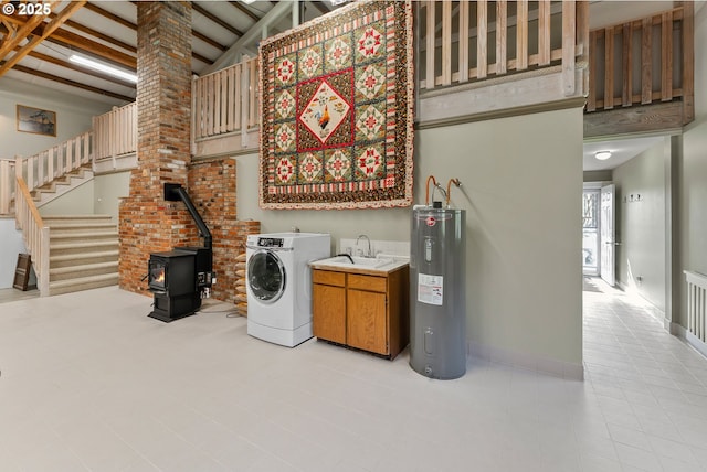 laundry room featuring a high ceiling, water heater, cabinet space, and a sink