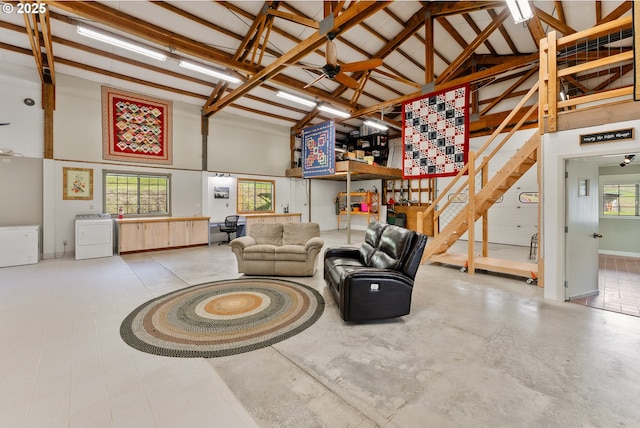 living area featuring high vaulted ceiling, washer / dryer, ceiling fan, and stairs