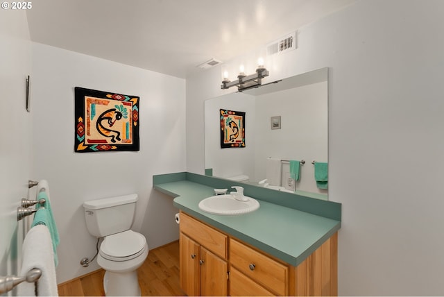 half bath with toilet, visible vents, and vanity