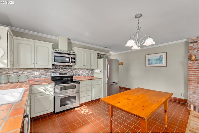 kitchen featuring tile countertops, appliances with stainless steel finishes, crown molding, and decorative backsplash