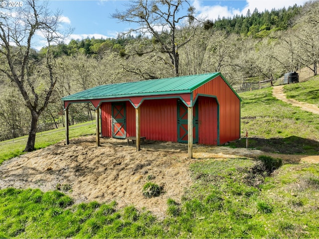 view of pole building featuring a forest view, fence, and a yard