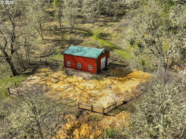 view of outdoor structure featuring driveway, a wooded view, an outdoor structure, and fence