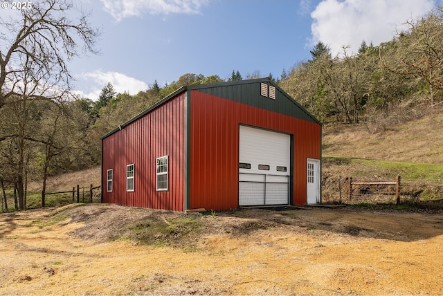 detached garage featuring fence and driveway