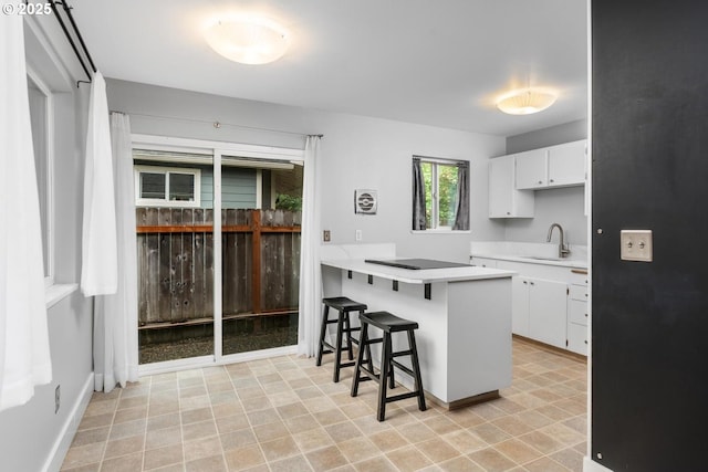 100 NE 78th Ave, Portland, OR 97213 - kitchen with a sink, white cabinetry, a kitchen bar, light countertops, and a peninsula