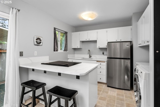 100 NE 78th Ave, Portland, OR 97213 - kitchen with freestanding refrigerator, washer and dryer, a sink, black electric cooktop, and a peninsula