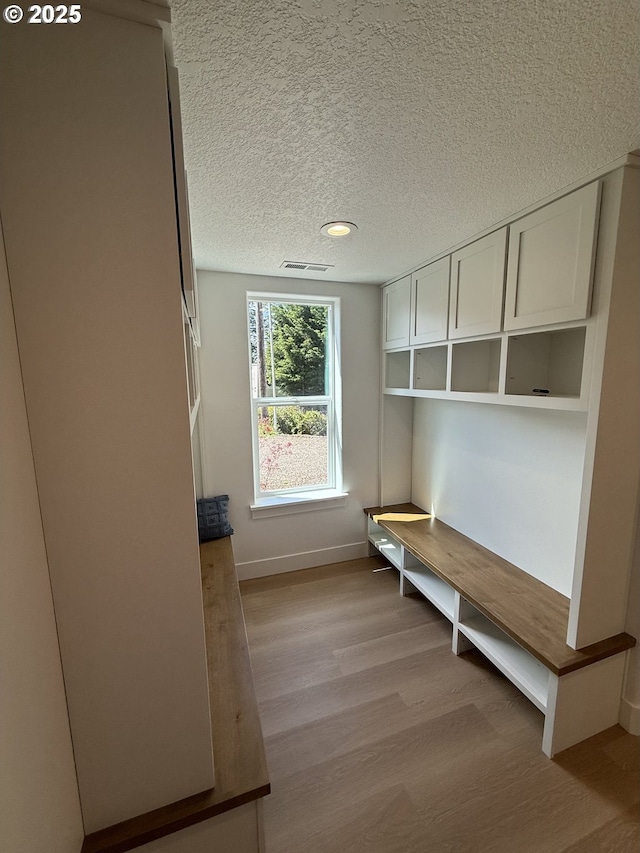 mudroom featuring light wood-style floors, a textured ceiling, recessed lighting, baseboards, and visible vents