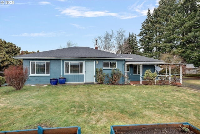 view of front of home with a front lawn, roof with shingles, a chimney, and concrete block siding