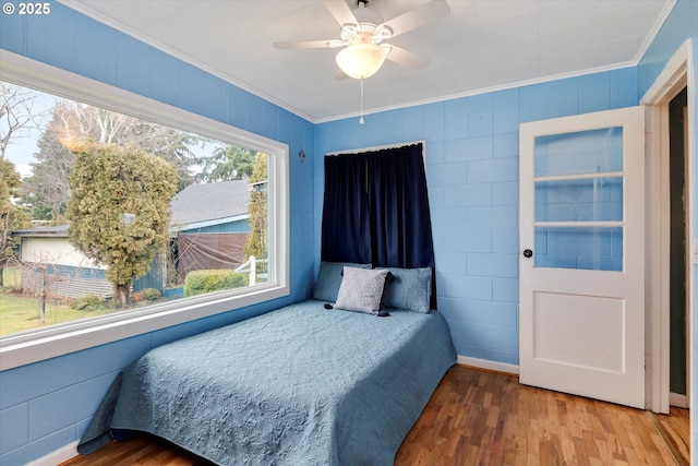 bedroom featuring a ceiling fan, crown molding, and wood finished floors