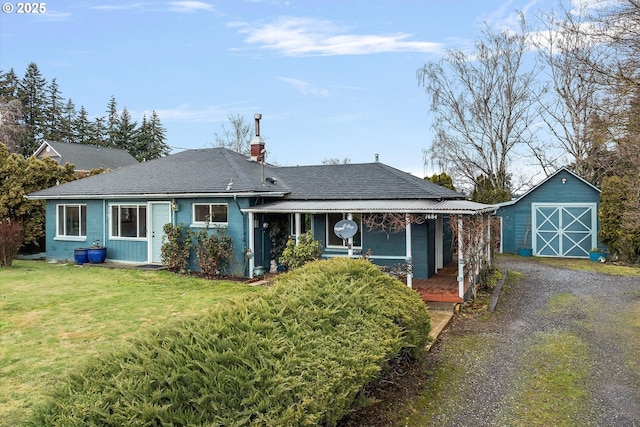 view of front facade featuring gravel driveway, a chimney, an outbuilding, and a front yard