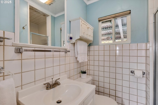 bathroom featuring toilet, ornamental molding, a shower with door, and tile walls