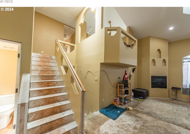 staircase with a glass covered fireplace and recessed lighting