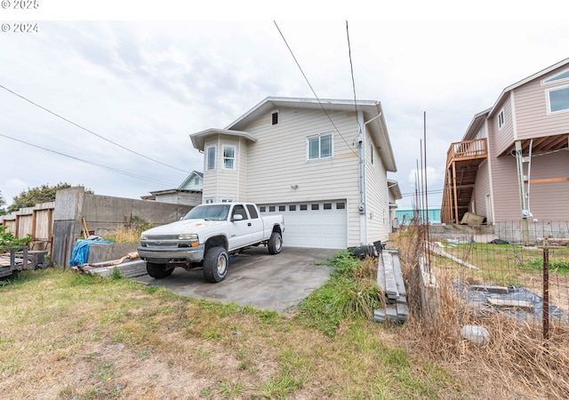 rear view of property with a garage, driveway, and fence