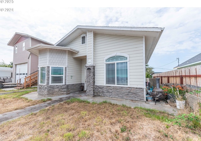 view of front of property featuring stone siding and fence