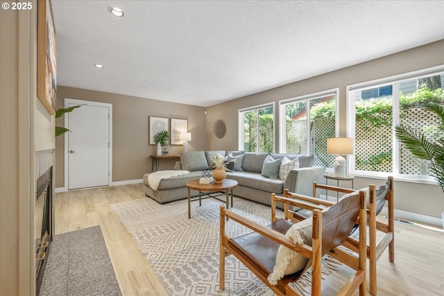 17221 SW Oakenshield Ct, Portland, OR 97224 - living room with a textured ceiling, light wood-style flooring, a tile fireplace, and recessed lighting