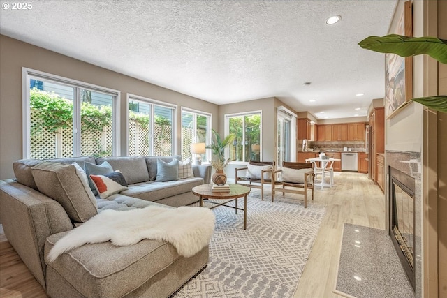 17221 SW Oakenshield Ct, Portland, OR 97224 - living area featuring light wood-style flooring, a textured ceiling, recessed lighting, and a high end fireplace