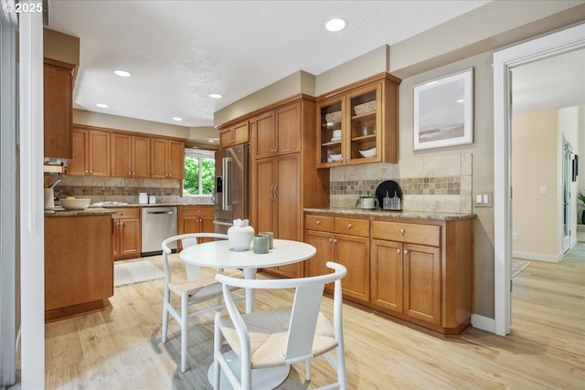 17221 SW Oakenshield Ct, Portland, OR 97224 - kitchen featuring appliances with stainless steel finishes, brown cabinetry, light wood-type flooring, decorative backsplash, and recessed lighting