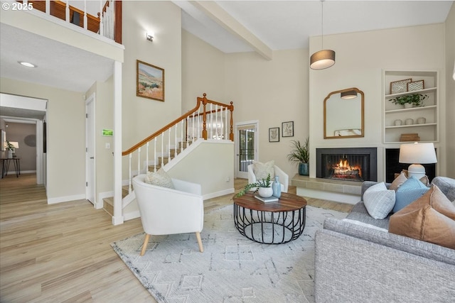 17221 SW Oakenshield Ct, Portland, OR 97224 - living area featuring wood finished floors, a tile fireplace, a high ceiling, stairs, and built in shelves