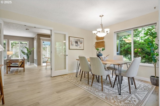 17221 SW Oakenshield Ct, Portland, OR 97224 - dining space featuring a chandelier, light wood-type flooring, plenty of natural light, and a textured ceiling