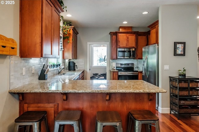 kitchen featuring stainless steel appliances, sink, backsplash, and kitchen peninsula