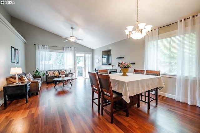 dining room with ceiling fan with notable chandelier, dark wood-type flooring, and vaulted ceiling