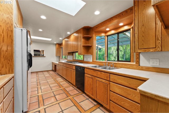 kitchen with a skylight, white refrigerator with ice dispenser, dishwasher, a sink, and recessed lighting