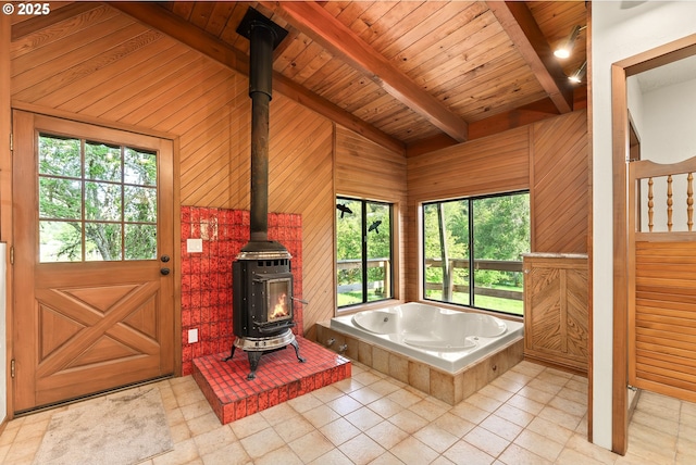 bathroom with wooden walls, plenty of natural light, a wood stove, and a garden tub