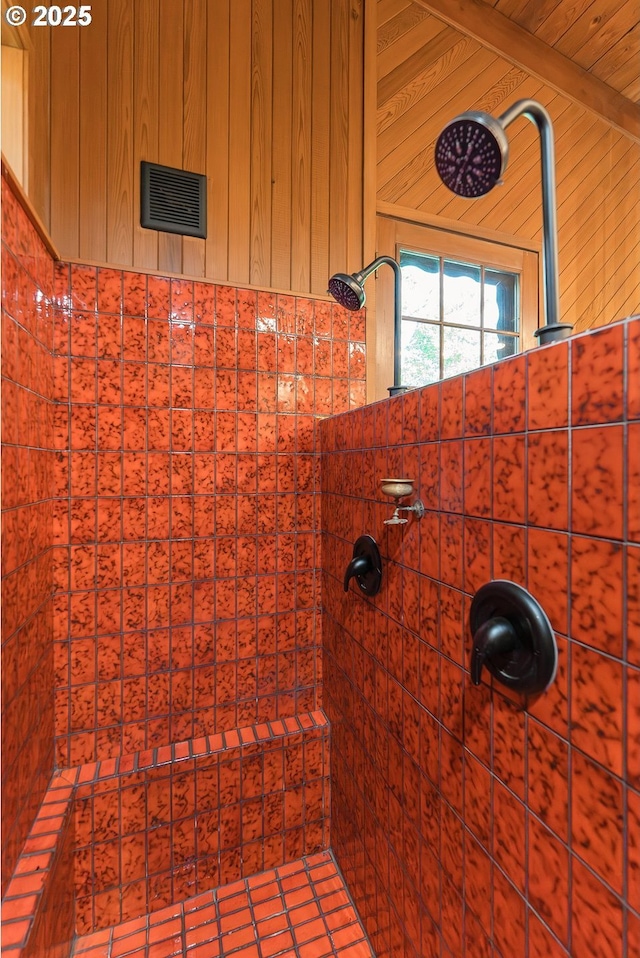 full bathroom featuring wooden walls, a tile shower, and visible vents