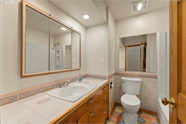 bathroom with vanity, toilet, tile patterned floors, tile walls, and visible vents