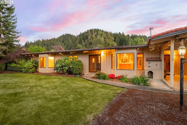 view of front of property featuring board and batten siding, fence, and a front yard