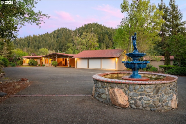 view of front facade featuring a view of trees, driveway, and a tile roof