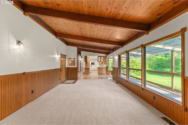 interior space with wood ceiling, wainscoting, wood walls, vaulted ceiling with beams, and light carpet