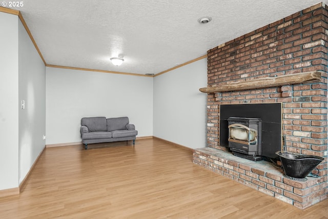 sitting room with a textured ceiling, ornamental molding, a wood stove, and hardwood / wood-style flooring