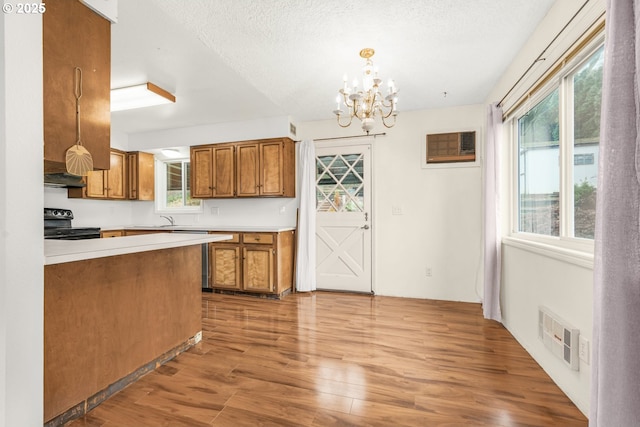 kitchen featuring electric range, a wall unit AC, a chandelier, hanging light fixtures, and extractor fan