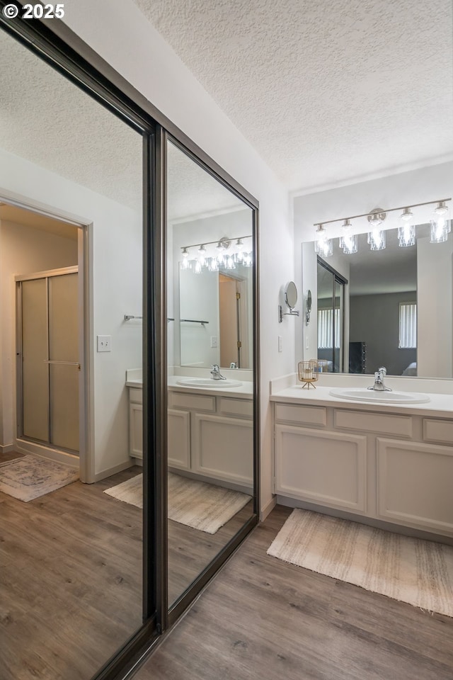 2024 Lake Isle Dr Unit 2024, Eugene, OR 97401 - bathroom featuring vanity, wood finished floors, a textured ceiling, and a stall shower