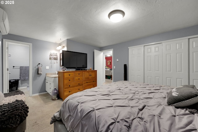 carpeted bedroom with ensuite bathroom, a textured ceiling, and a wall mounted AC