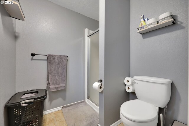 bathroom featuring tile patterned floors, toilet, and a shower with door