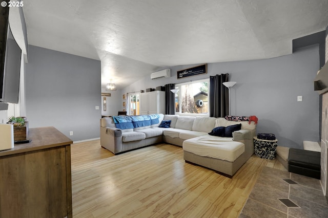 living room with an AC wall unit, lofted ceiling, and light wood-type flooring