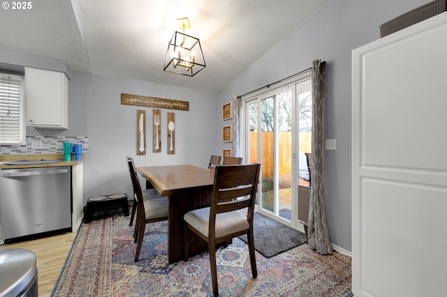 dining space with vaulted ceiling, light hardwood / wood-style flooring, and an inviting chandelier